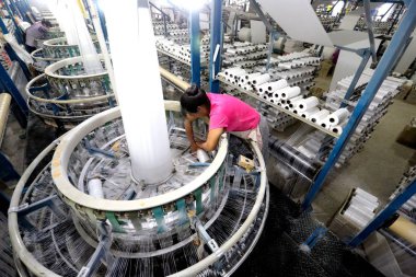 A female Chinese worker handles production of yarn at a textile factory in Huaian city, east China's Jiangsu province, 29 May 2017 clipart