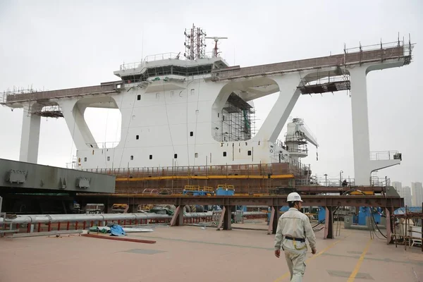 A Chinese worker walks past the world's largest bulk carrier ''Ore Tianjin'' at a port in Qingdao city, east China's Shandong province, 10 October 2017 — Stock Image Chinese Worker Walks World Largest Bulk Carrier Ore Tianjin Port Stock Image
