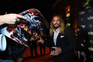 American actor and model Jason Momoa signs autographs for fans as he arrives on the red carpet for the movie 