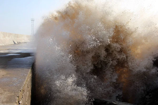 Waves from a tidal bore caused by Typhoon Lan surge past a barrier on the banks along the seacoast in Wenling city, east China\'s Zhejiang province, 21 October 2017