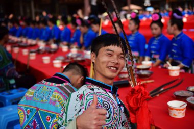 A Chinese young man of Miao ethnic minority dressed in traditional clothes poses at the 2,140-meter long table banquet during the Double Ninth Festival at Wanda tourism town in Danzhai county, Qiandongnan Miao and Dong Autonomous Prefecture, southwes clipart