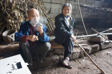 Elderly Chinese couple Liang Zifu, left, and Li Suying sit outside a cave, which they have lived in for 54 years, near Nanchong city, southwest China's Sichuan province, 24 September 2016 clipart