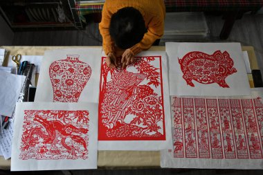 A craftswoman makes a paper-cutting artwork at a workshop in Yantai city, east China's Shandong province, 10 January 2019 clipart