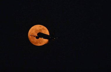 A jet plane flies across the supermoon in Xiamen city, southeast China's Fujian province, 13 December 2016 clipart