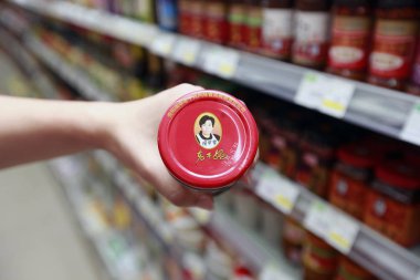 A shopper buys a bottle of Lao Gan Ma or Laoganma chili sauce at a supermarket in Zhengzhou city, central China's Henan province, 23 July 2016 clipart
