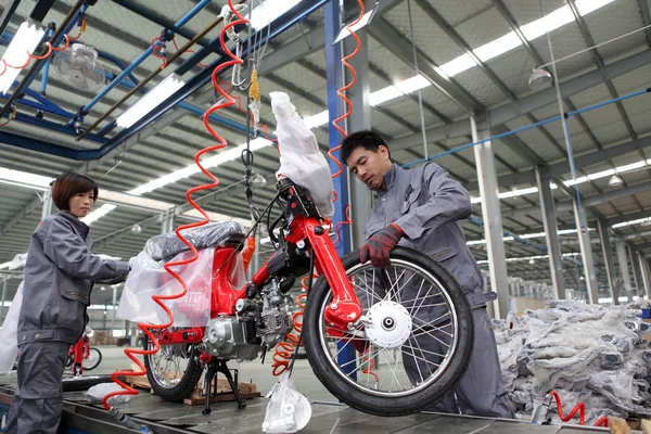中国の労働者は 中国のオートバイ会社の工場で組み立てラインにバイクを組み立てます 11月 2016 — ストック写真