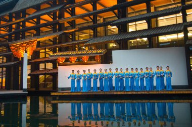 Volunteers wearing cheongsam (qipao) with phoenix decoration pose in front of the Wuzhen Internet International Convention Center before the upcoming 3rd World Internet Conference (WIC), also known as Wuzhen Summit, in Wuzhen town, Tongxiang city, ea clipart