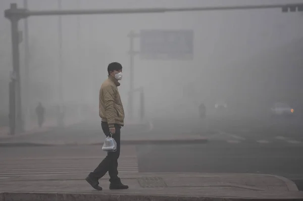 2016年12月19日 中国天津 一名戴着防空气污染面罩的行人在浓雾中横穿马路 — 图库照片