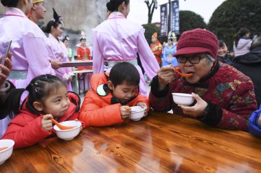 Visitors enjoy Laba Congee, or Eight Treasures Porridge, made by Chinese workers dressed in traditional costume in a giant iron pot with a diameter of 8 meter at the Mingyue Mountain forest park in Yichun city, east China's Jiangxi province, 12 Janua clipart
