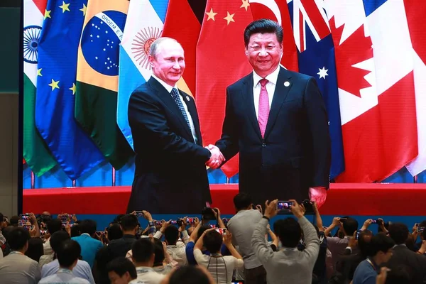 记者在2016年9月4日于中国东部浙江省杭州举行的二十国集团杭州峰会上与俄罗斯总统普京握手 记者们合影或观看了中国国家主席习近平的直播 — 图库照片
