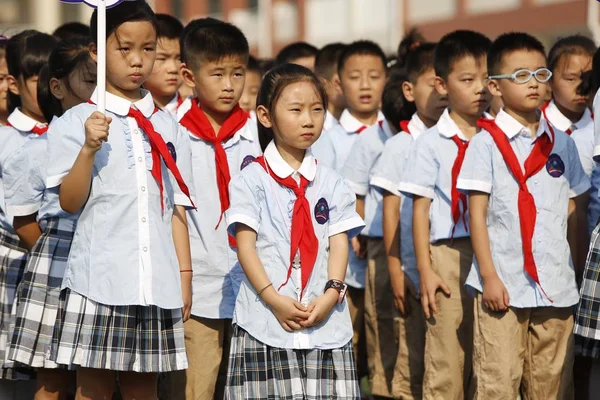 Young Chinese students attend a flag-raising ceremony at a primary school on the first day of the new semester in Lianyungang city, east China\'s Jiangsu province, 1 September 2016