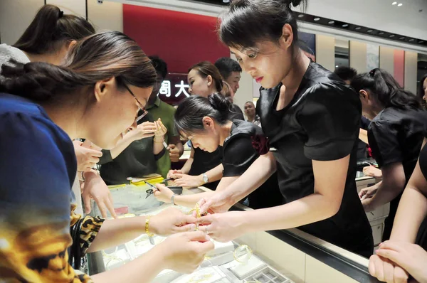 中国店員 2016 日中国東部の山東省済南市の宝石店で金の装飾品を試してみるの買い物客を支援します — ストック写真