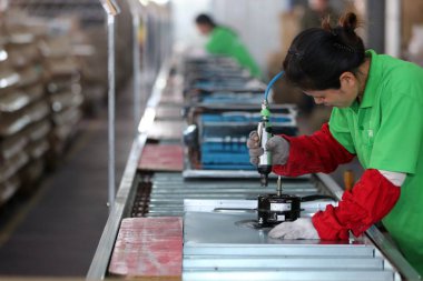 A female Chinese worker manufactures air conditioners at a factory in Huaian city, east China's Jiangsu province, 14 May 2016 clipart