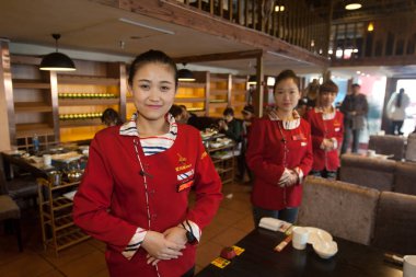 Chinese waitresses prepare to serve customers at a restaurant in Changchun city, northeast China's Jilin province, 13 January 2015 clipart