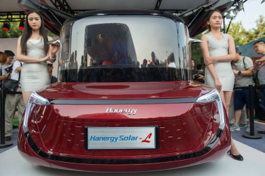 Models pose with a Hanergy Solar L solar-powered car at a launch event in Beijing, China, 2 July 2016 clipart