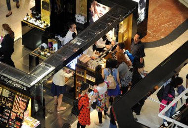 Chinese customers shop for cosmetics and skincare products at a counter of Yves Saint Laurent (YSL) at the Galeries Lafayette department store during the 2016 