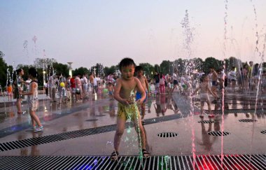 Chinese children play with water in a fountain to cool off on a scorching day in Tongling city, east China's Anhui province, 25 July 2016.  clipart