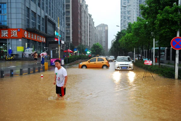 2016年6月19日 中国中部湖北省武汉市 一名男子在大雨中走在被洪水淹没的公路上 — 图库照片