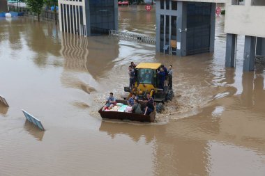 Local Chinese residents are evacuated by wheel loader from a flooded road caused by heavy rain in Anyang city, central China's Henan province, 20 July 2016 clipart