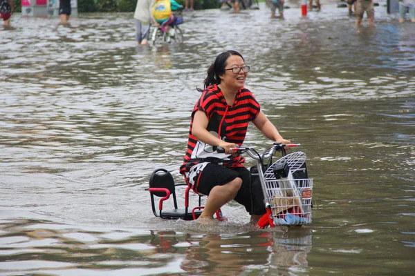 2016年7月20日 在中国北部的河北省汉丹市 一名中国自行车手在大雨造成的严重淹没道路上骑着电动自行车时做出反应 — 图库照片