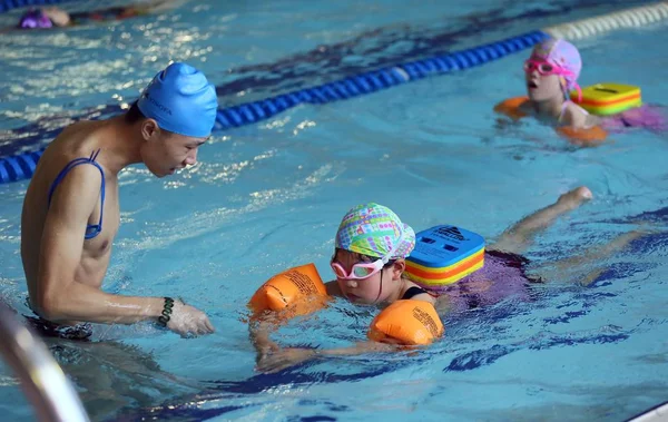 中国のコーチは非常に熱いものにプール スイミング ホールで 2016 日中国東部の江蘇省南通市で夏休み中に水泳を学ぶ若い女の子を指示します — ストック写真