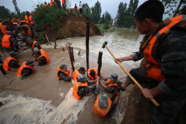 Chinese PLA (People's Liberation Army) soldiers try to block the breach of a dyke caused by heavy rain in Caoma village, Cuijiaqiao town, Anyang city, central China's Henan province, 20 July 2016 clipart