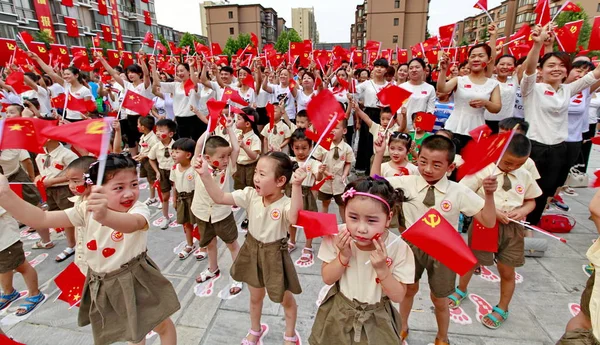 中国の若い子供たちと地元住民は 中国の山西省の北部 雲城市の住宅街でCpcの設立95周年を祝うためのガラ中に中国と中国共産党の旗を振っています — ストック写真