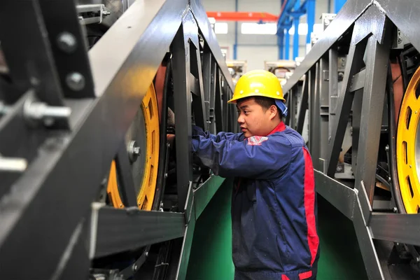 stock image  Chinese worker assembles an escalator at a factory in Yichang city, central China's Hubei province, 24 March 2016