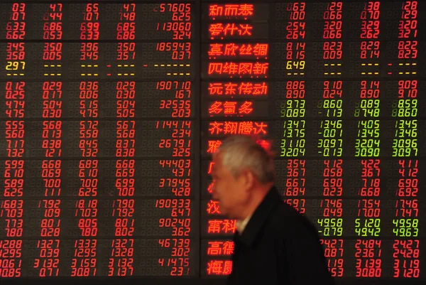 2016年4月11日 中国东部安徽省阜阳市一家股票经纪公司 一位中国投资者走过显示股价的电子板 价格上涨为红色 价格下跌为绿色 — 图库照片