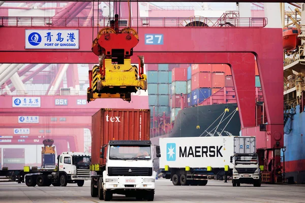 トラックは 2016 中国東部の山東省青島市の青島港の岸壁にコンテナー船からコンテナーを輸送します — ストック写真