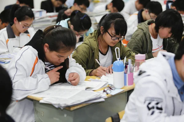 中国人留学生が今後国立大学入学試験とも呼ばれる Gaokao 2016 日中国東部の江蘇省連雲港市楡 号高校で教室での準備のために教科書を確認します — ストック写真