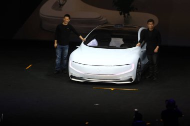 Jia Yueting, left, founder, Chairman and CEO of Letv, and Ding Lei, vice-chairman of LeTV Super Car, pose with LeSEE self-driving electric car at a launch event in Beijing, China, 20 April 2016. clipart