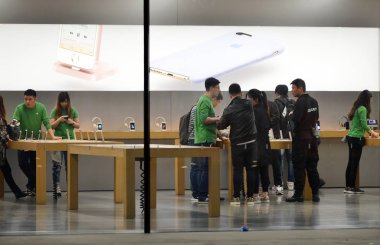 Chinese employees wearing green tee shirts to mark the World Earth Day serve customers at an Apple Store in Shenyang city, northeast China's Liaoning province, 20 April 2016. clipart