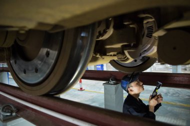 A Chinese technician examines a CRH (China Railway High-speed) bullet train at a maintenance station in Shenzhen city, south China's Guangdong province, 31 January 2016 clipart