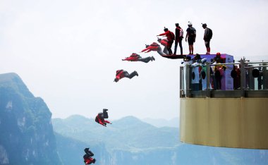 Contestants jump off the glass cantilever bridge on the cliff during the 2016 World Low-Altitude Parachute Jump contest in Longgang scenic area in Yunyang county, Chongqing, China, 27 April 2016 clipart