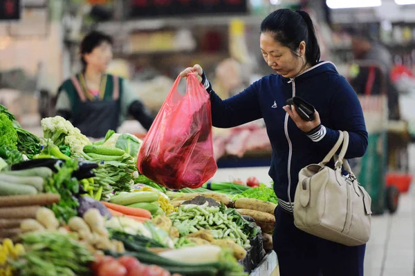 中国の顧客は青島市 東中国山東省の自由市場で野菜を買うように使い捨ての袋を使用します 月2013 — ストック写真