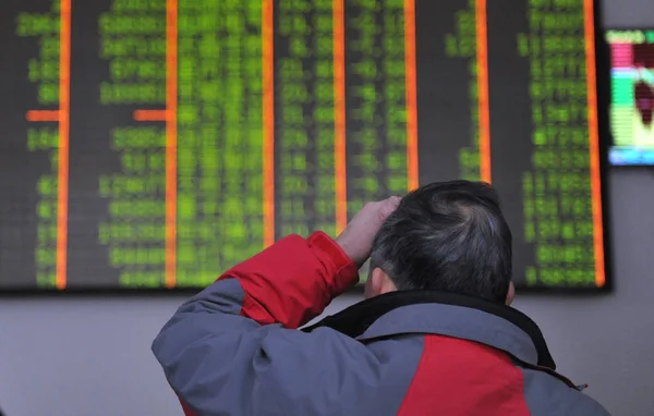 一位中国投资者看了中国东部浙江省杭州市一家股票经纪公司的股价 价格上涨为红色 价格下跌为绿色 2016年2月1日 — 图库照片