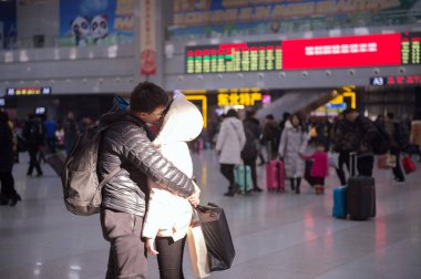 A couple of Chinese lovers kiss each other to bid farewell at the Changchun Railway Station as they are going to part and spend the Chinese Lunar New Year, also known as Spring Festival, with their own families respectively in Changchun city, northea clipart