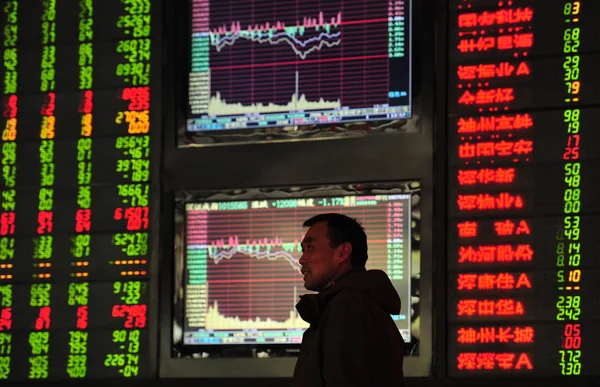 2016年3月29日 在中国东部安徽省阜阳市一家股票经纪公司 一位关心此事的中国投资者走过显示股指和股价的屏幕 价格上涨为红色 价格下跌为绿色 — 图库照片