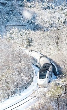 A CRH (China Railway High-speed) bullet train travels through the snow-clad apricot trees near the Juyongguan Great Wall at Juyong Pass in Beijing, China, 23 November 2015 clipart