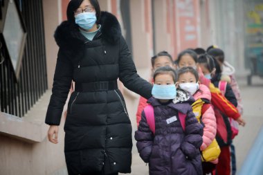 Chinese pupils and their teacher wearing face masks against air pollution walk towards their school in heavy smog in Jinan city, east China's Shandong province, 24 December 2015 clipart