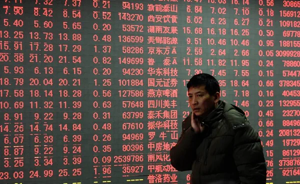 在中国东部浙江省杭州市一家股票经纪公司 一名中国投资者走过显示股价 价格上涨为红色 的屏幕 — 图库照片