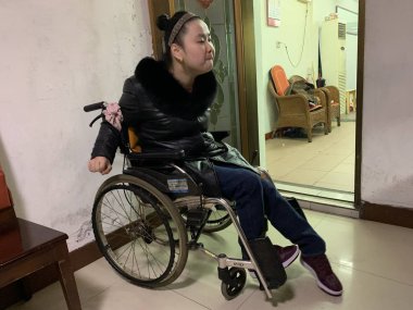 26-year-old Chinese woman Wang Qianjin born with cerebral palsy sit on a wheelchair at home in Zhenjiang city, east China's Jiangsu province, 24 January 2019 clipart