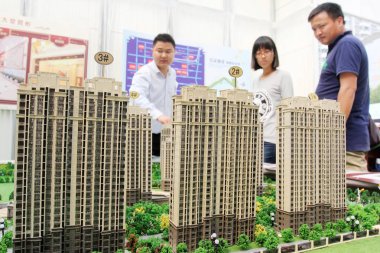 A Chinese employee introduces models of residential apartment buildings to homebuyers during a real estate fair in Haian city, east China's Jiangsu province, 1 October 2015 clipart