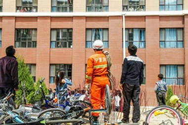 A Chinese firefighter is seen under a dormitory building to save a girl considering suicide at Beifang University of Nationalities in Yunchuan city, northwest China's Ningxia Hui Autonomous Region, 23 April 2015 clipart