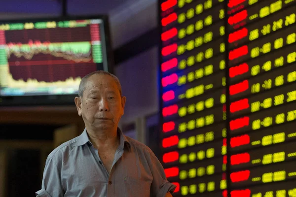 中国の投資家は 2015 日中国東部の江蘇省南京市の証券の家で株式 価格下落のためグリーン の価格を示して表示を過ぎて歩く — ストック写真