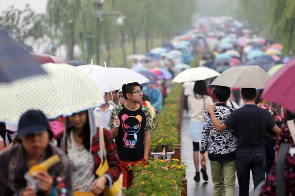 2015年10月4日 在中国东部浙江省杭州市 在雨中 拿着雨伞的游客沿着西湖走在一条堤道上 — 图库照片