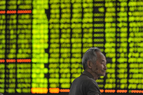 2015 日東中国江西省南昌市の証券会社の家で株式 価格下落のためグリーン の価格を表示する画面の前に懸念している中国語の投資家が描かれています — ストック写真