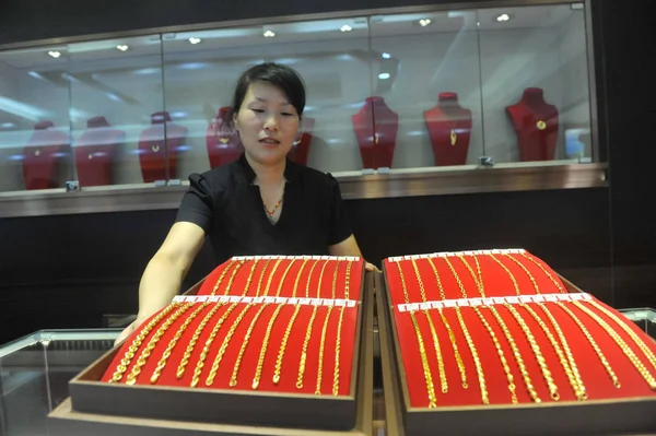 中国の従業員は 2015 日中国東部の浙江省臨安市の宝石店で金のネックレスを表示します — ストック写真