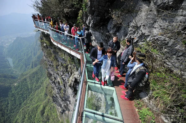 または Tianmenshan で張り家界市で張り家界国家森林公園 崖の上ガラス スカイウォークを歩く観光客中国中央部湖南省 2015 — ストック写真